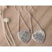 Sterling silver trillion shape imprinted with a mandala design hanging from sterling silver chain from two corners and a sterling ear wire. 