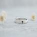 Sterling silver ring with a cross on a white wooden background with flowers. 