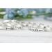Sterling silver name rings on a white wood surface with floral background. 