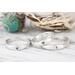 Sterling silver heart and cross rings on a white wood surface with floral background. 