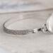 Handcrafted sterling silver wildflower oval cuff bracelet from Alaska, with textured band, on floral paper. 
