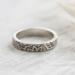 Detailed view of a sterling silver floral ring on wood, emphasizing its unique 4mm texture.

