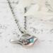 Sterling silver bird necklace with turquoise, on a white surface.
