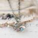 Sterling silver bird necklace with turquoise, on a white surface.
