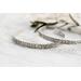 A pair of sterling silver cuff bracelets with an embossed floral pattern, displayed on a rustic white wooden surface.