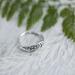 Close-up of vintage sterling silver leaf ring on white wood, eco-friendly, sizes 3-10.  
