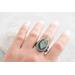 Silver ring with pear-shaped faceted labradorite featuring blue-green opalescent flashes serrated bezel and bead detailing around the bezel.