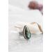 Silver ring with pear-shaped faceted labradorite featuring blue-green opalescent flashes serrated bezel and bead detailing around the bezel.