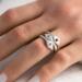 Hand wearing three sterling silver stackable rings with lowercase initials "a," heart, and "t" on a white  background with dried flowers
