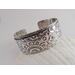 Wide sterling silver bracelet with floral textured overlay.