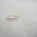 Close-up of a sterling silver daisy ring with embossed floral design on a soft, blurred background.

