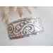 Wide sterling silver cuff bracelet with layered scrollwork pattern. 