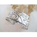 Wide sterling silver cuff bracelet with layered scrollwork pattern. 