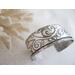 Wide sterling silver cuff bracelet with layered scrollwork pattern. 