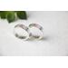 "Two silver bands with personalized engraving, 'JOHN' and 'PSALMS" visible, on a white fabric with green leaves in the background."
