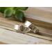 Two sterling silver wedding bands, one hammered, on rustic wood with green leaves backdrop, showcasing customizable texture options.