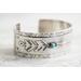 Sterling silver cuff bracelet with embossed arrow overlay accented with a genuine turquoise cabochon. 