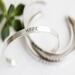  Sterling silver bracelet with the word HOPE, on a white surface with a green succulent in the background.
