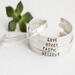 Five sterling silver bracelets with words HOPE, LOVE, GRACE, FAITH, BELIEVE, on a white surface with a green succulent in the background.
