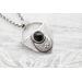 Shield shaped sterling silver pendant with floral patterned moon and faceted black onyx cabochon. 