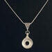 French model open hole flute key crafted in silver and suspended on an antique bail and snake chain.