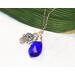 Image is of a Blue Crystal Teardrop Pendant with a Silver Hama Hand charm wire wrapped on a chain. 25" long
