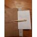 One bone nalbinding needle, atop its packaging prior to shipping.