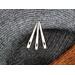 Three bone nalbinding needles on a background of black, gray, and brown nalbound fabric.