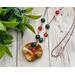 Necklace with wavy copper pendant flame colored to bring out red and yellow hues, red agate, malachite, and citrine beads on copper chain.