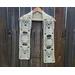 White Mom Crochet Scarf display on a hanger in front of a wooden fence.