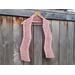 Display of the Zig Zag Crochet Scarf on a hanger in front of a wooden fence.