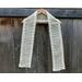 Display of the Diagonal Crochet Scarf Pattern on a hanger in front of a wooden fence.