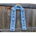 Snowman outlines along a light blue scarf in front of a wooden fence.