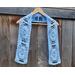 Display of the Easter Crochet Scarf on a hanger in front of a wooden fence.