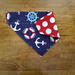 Over the collar dog bandana that is reversible from anchors to red with white polka dots.