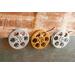 front view of a gold and silver miniature movie reel magnets hanging on fridge