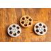 top view of a three miniature movie reel magnet in gold and silver sitting on a wooden table