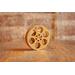 front view of a gold miniature movie reel magnet sitting on a wooden table