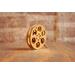 side view of a gold miniature movie reel magnet sitting on a wooden table
