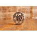 side view of a silver miniature movie reel magnet sitting on a wooden table