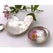 Set of three nesting trinket dishes made from a vintage silverplated brass serving tray. Largest dish is a bird shape, two smaller dishes are round. Photo shows all three side by side, one with tiny rose blossom floating in water.