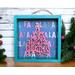 A small shadow box with a fa la la insert that has a wooden christmas tree that says a very merry holly jolly christmas attached.