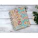 A blank handmade notebook with peach color lined paper that has a paisley cover