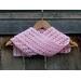Display of the Shell Crochet Scarf on a hanger in front of a wooden fence.