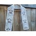 Display of the Ghost Crochet Scarf on a hanger in front of a wooden fence.