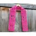 Display of the Tulip Crochet Scarf Pattern on a hanger in front of a wooden fence.