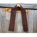 Display of the Grid Crochet Scarf on a hanger in front of a wooden fence.