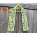 Display of the Leaf Crochet Scarf on a hanger in front of a wooden fence.