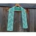 Display of the Vine Crochet Scarf on a hanger in front of a wooden fence.