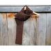 Display of the Grid Crochet Scarf on a hanger in front of a wooden fence.